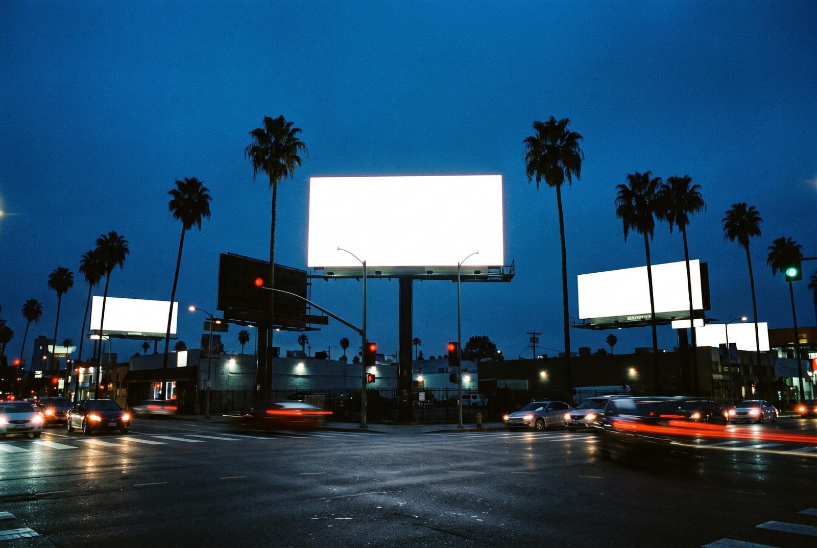Blank illuminated billboards over a Los Angeles intersection at dusk